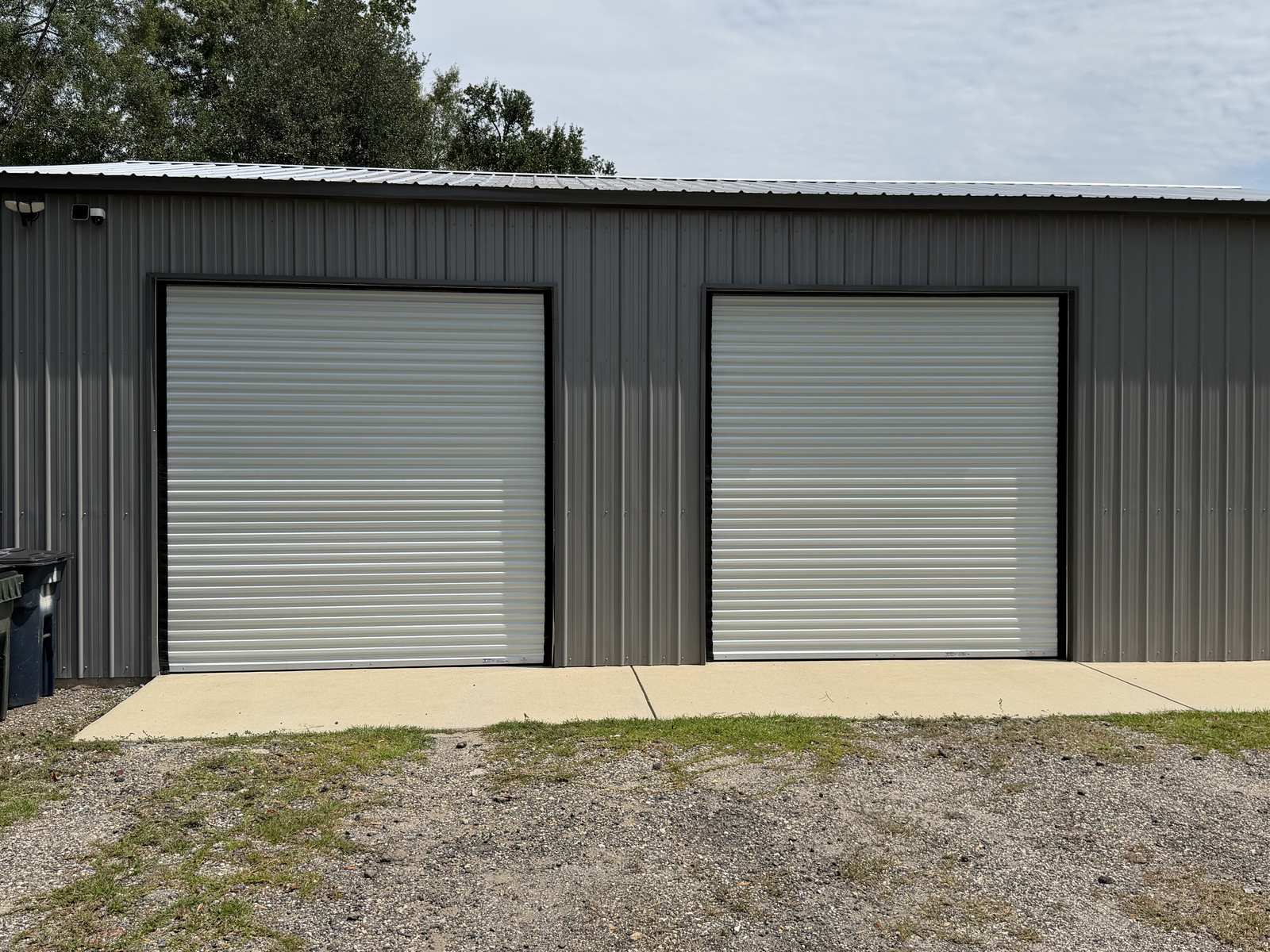 Two white roll-up doors installed on a metal building
